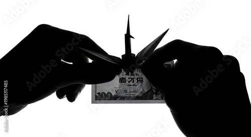 A silhouette of hands cutting a Japanese banknote with scissors