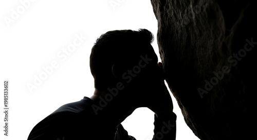 A silhouette of a man kissing a rock formation against a bright white background