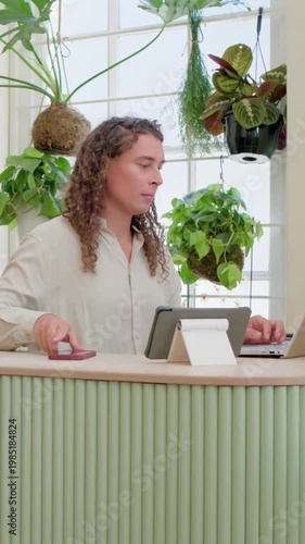 Vertical video: Checking phone person typing on laptop and writing in notebook at counter for work