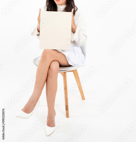 Asian woman body in white short skirt sitting on chair holding plain gift box, isolated on white background