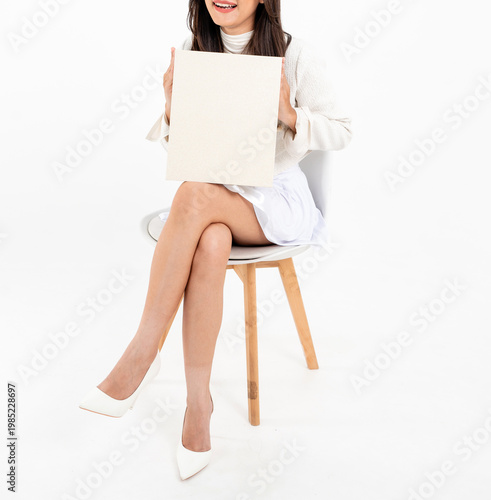 Asian woman body in white short skirt sitting on chair holding plain gift box, isolated on white background