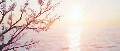 Pink blossoms frame a soft, warm sunset over tranquil water with gentle reflections, creating a serene glow