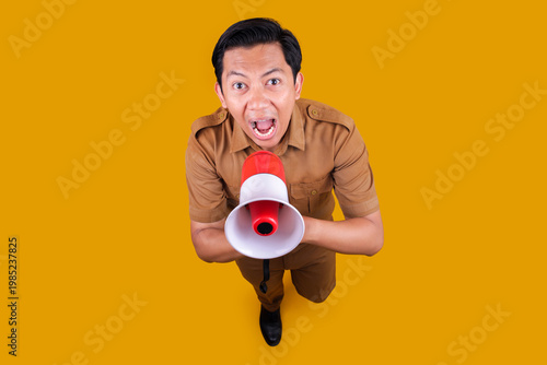 Foto Asian Male Civil Servant in Brown Uniform Shouting Through Megaphone