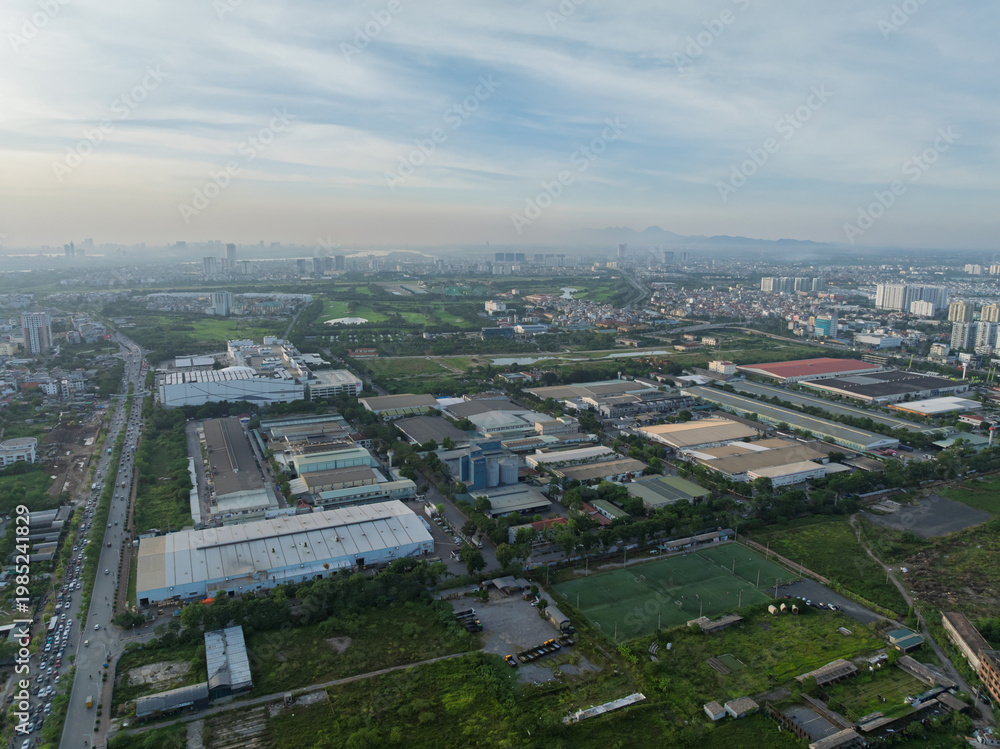 Fototapeta premium Aerial daytime view of an industrial cluster in Long Bien district, Hanoi, showing factories, warehouses, roads, and surrounding urban and green areas.