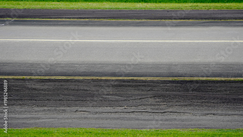 Картината върху платно Detailed view of asphalt taxiway surface with yellow painted lines for aircraft navigation and guidance at the airport ground area