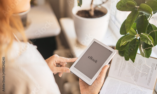 Minimalist scene with ebook reader, plant and open book. Calm composition promotes mindful reading, slow living and focus on personal growth, balance and peaceful daily routine at home