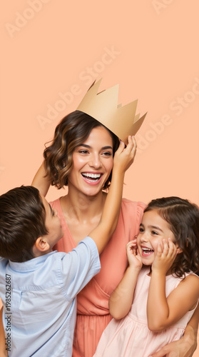 Vertical portrait of a happy mother being crowned by her children. Smiling woman with son and daughter on peach background. Queen for a day Mother's Day concept
