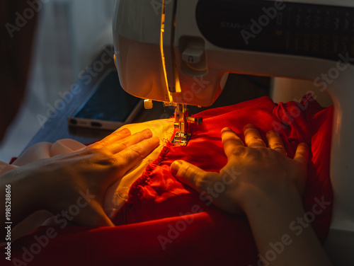 Foto Hands sew fabric with sewing machine in evening light