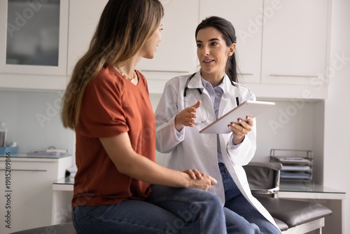 Bild auf Leinwand Professional Latina therapist holding modern digital tablet during conversation with woman patient, accessing electronic health record system, explain treatment plan or health test results