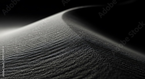 Sand dune crest features subtle ripples under dramatic lighting.