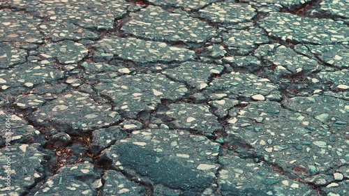 Cracked asphalt road surface with rough broken pavement texture