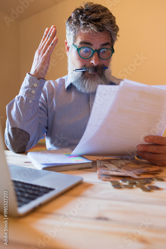 Man looking stressed reading financial documents receiving bad news