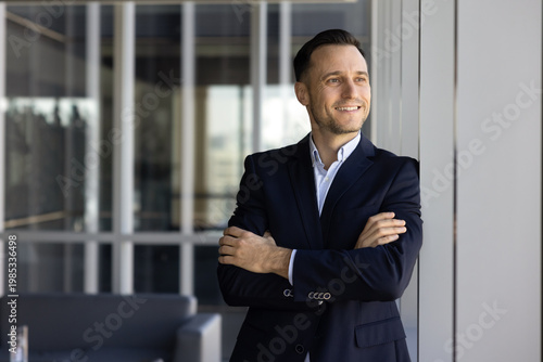 Confident businessman stands with folded arms, looks into distance thoughtfully, thinks on future opportunities, represent leadership in business, professional success, career growth and achievements