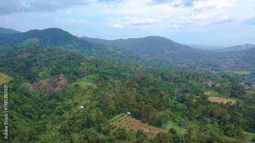 A sweeping drone shot captures the majestic green ridges and deep valleys of the North Sumatra highlands