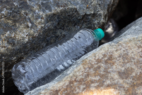 Plastic water bottles thrown between the rocks, plastic pollution. Climate change issues with the plastic wastes.