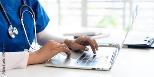  professional  doctor using laptop computer in hospital office watching medical webinar training, writing in healthcare report,