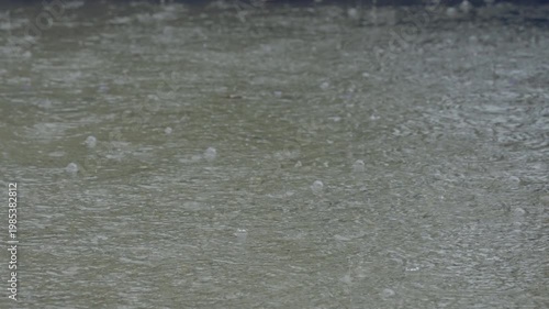 Close-up of raindrops splashing into a puddle during a rainy suburban storm. Captures the peaceful and dramatic moment of rainfall in high detail