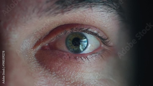 Doomscrolling man eye close up with smartphone news feed reflection in glasses at night. Man scrolling news on phone, endless news feed glowing in eye, digital addiction, information overload