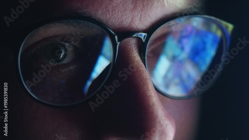 Close up male eyes in glasses reflecting smartphone news feed scrolling rapidly at night. Concept information overload constant online news monitoring, endless search for digital information in media