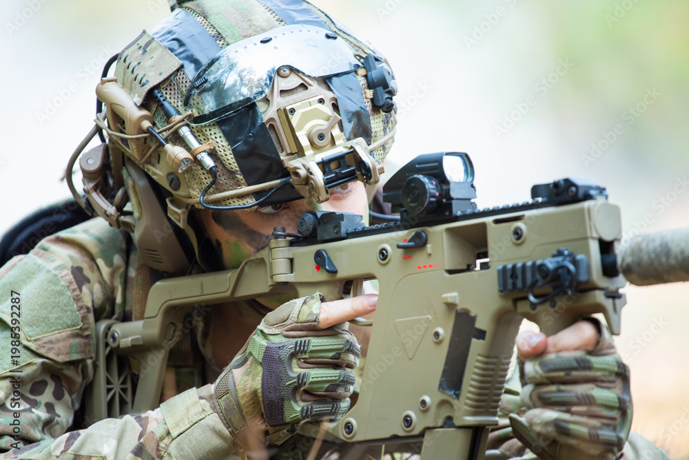 Fototapeta premium Two Soldiers Collaborating on Tactical Operations with Assault Rifles in a Camouflaged Environment, One Soldier Wearing a Green Assault Rifle and Camouflage Gear, Observing with a Red Sight, Preparing
