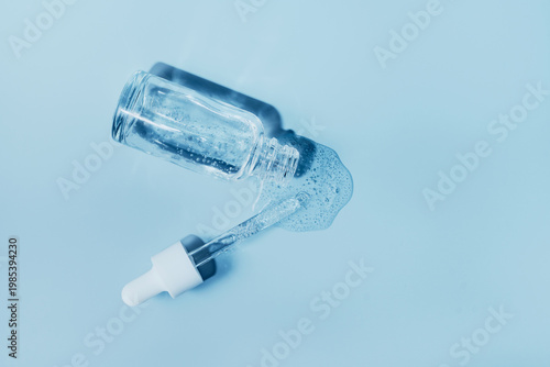 Fotografija Cosmetic serum bottle with dropper spilling clear liquid promoting skin care