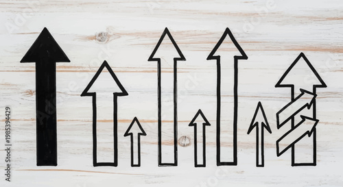 A row of various upward-pointing arrows, some solid black and others outlined, symbolizing growth and progress on a wooden background.