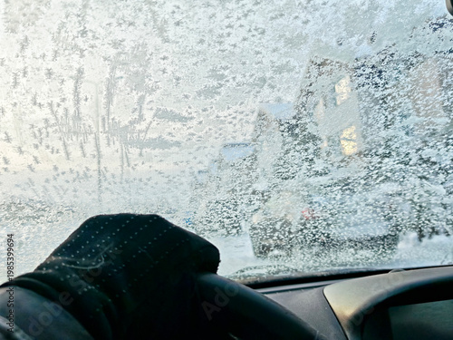 Driving in winter with icy windshield and frosted glass while facing snowy road ahead in cold weather conditions