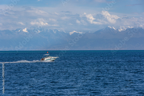 Speedboat with red national flag of Kyrgyzstan racing across waves of Issyk-Kul lake