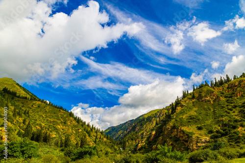 Majestic mountain valley with green hills and blue sky in Kyrgyzstan