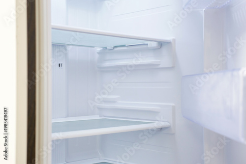Modern open refrigerator close-up with empty shelves, side view.