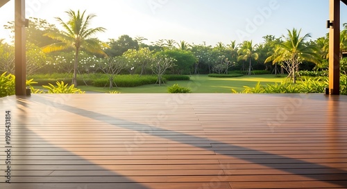 Wooden deck overlooking lush tropical garden at sunrise with palm trees and vibrant green foliage illuminated by golden sunlight
