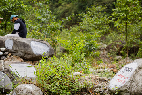 Photography A man sits on a large rock in a serene natural setting near Madhyamaheshwar temp