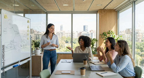 A diverse group of women in a modern office setting are engaged in a brainstorming session. 