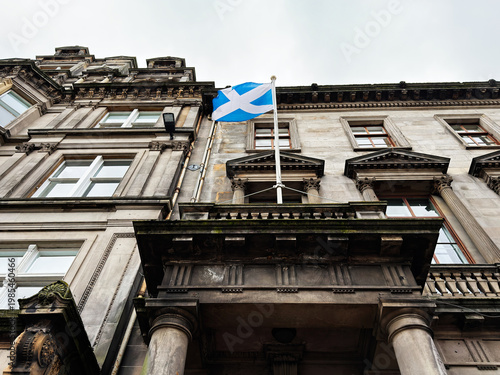 Scottish flag above historic stone building facade in Edinburgh, Scotland, UK, classical architecture with columns and ornate details