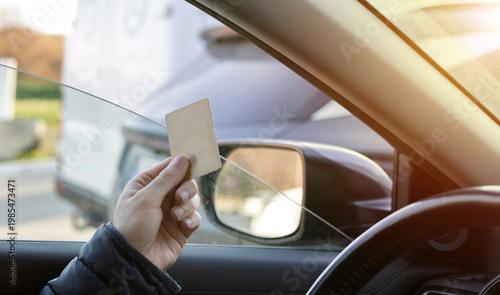 Man sitting in car at gas station during fuel crisis,checking empty wallet and holding payment card.Concept of rising fuel prices.Driver leaning on steering wheel.Close of fuel nozzle into car tank.
