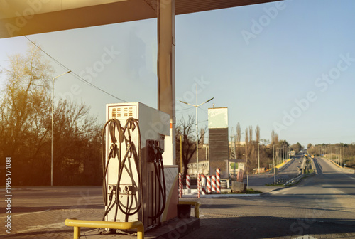 Man sitting in car at gas station during fuel crisis,checking empty wallet and holding payment card.Concept of rising fuel prices.Driver leaning on steering wheel.Close of fuel nozzle into car tank.