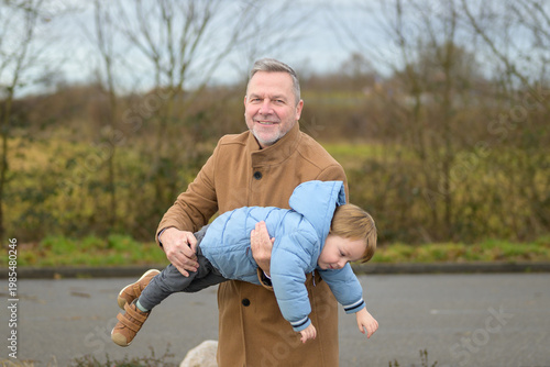 Grandfather Carrying Toddler Outdoors Winter