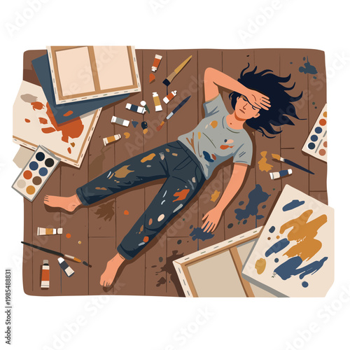 A woman lies on a wooden floor surrounded by painting supplies and canvases