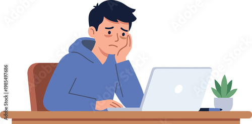 Frustrated man sitting at desk working on laptop with plant