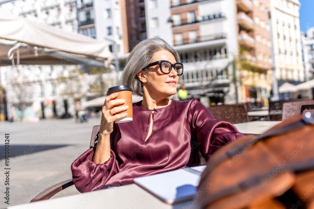 Fototapeta premium Elegant woman enjoying coffee at outdoor urban cafe