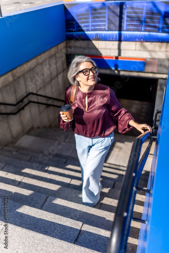Cuadro en lienzo Woman ascending metro stairs holding coffee cup