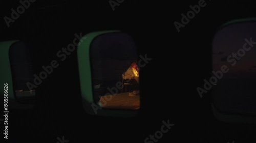 Asian couple on honeymoon enjoying a candlelight dinner outdoors, seen through a window, creating an intimate and cinematic date night atmosphere. 