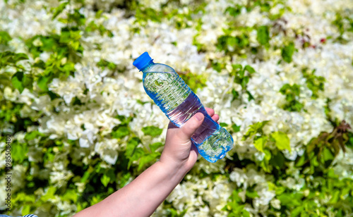 Wallpaper Mural A girl holds a bottle of drinking water on a background of white flowers
 Torontodigital.ca