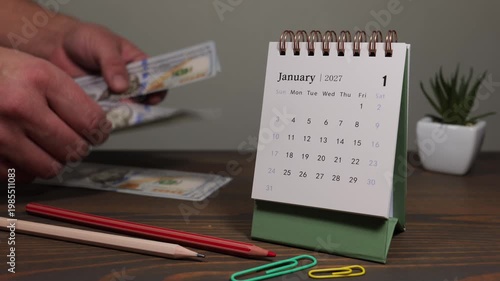 January 2027 Calendar with Person Counting Money on Desk Financial Planning Concept
