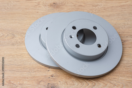 Tableau sur toile Pair of brand new ventilated metal brake rotors placed on a wood surface