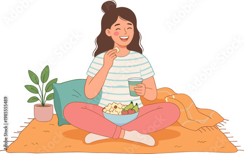 Woman eating salad and drinking from a glass while sitting on a blanket indoors.
