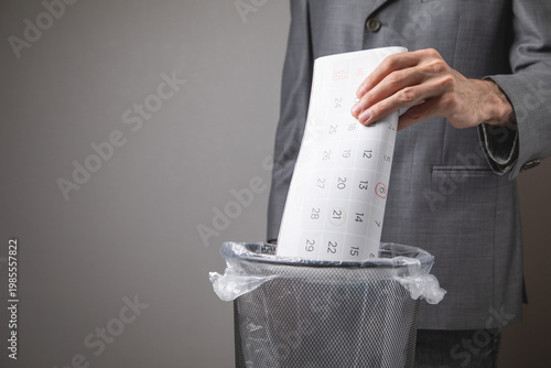 Photos Man throwing calendar into rubbish bin.