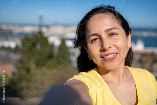 Smiling woman taking a selfie, enjoying vacation and lifestyle in a sunny outdoor setting
