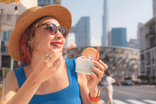 Εκτύπωση καμβά Woman smiling, experiencing a refreshing moment with gelato in front of Dubai's