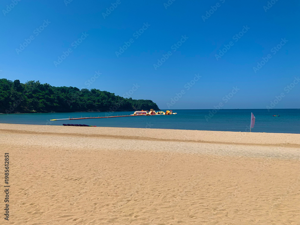 Obraz premium Beach view of the sand and ocean with inflatable island